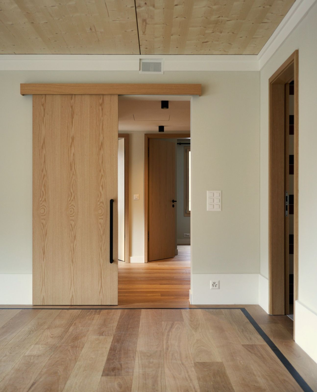 An oak veneer sliding barn door in a bright residential hallway
